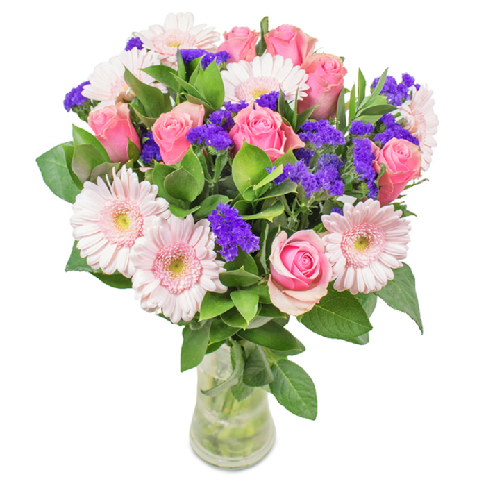 An elegantly composed bouquet from Battersea, artfully arranged in a crystal-clear glass vase and photographed against a bright white background. The focal point is an appealing mix of seven to nine soft-to-medium pink roses-some tightly curled, others just unfurling their velvety petals-intertwined with five to seven pale pink gerbera daisies, whose broad, symmetrical petals and lighter centers draw the eye. Clusters of vivid purple statice, characteristic of UK summer fields, are thoughtfully dispersed, adding textural contrast and a splash of deeper color. The arrangement is anchored by lush, deep green foliage reminiscent of walks through Battersea Park, lending visual freshness and natural abundance. Visible stems and shimmering water inside the vase emphasize its vibrant, delivered-today quality. This bouquet, suitable for birthdays, anniversaries, Mother's Day surprises, or as a cheerful accent for a St. John's Hill home or office, speaks of genuine affection, celebration, and the creative touch of a Battersea florist.